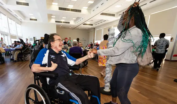 A person in a wheelchair and a standing woman dancing together